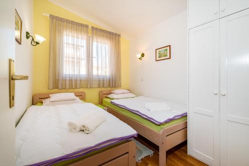 2 Betten in einem kleinen Zimmer mit Fenster in der Unterkunft Apartments by the sea Privlaka, Zadar - 18652 in Privlaka