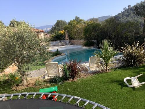 a backyard with a swimming pool with chairs and a lawn at Villa luxueuse in Peypin