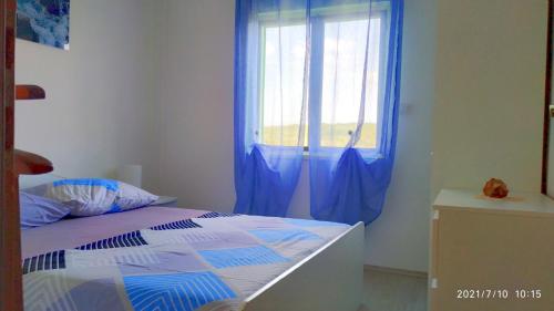 a bedroom with a bed and a window with blue curtains at Apartments by the sea Necujam, Solta - 18664 in Grohote