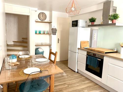 een keuken met een tafel en een koelkast bij Thuir, Charmante Maison T2 Climatisée in Thuir