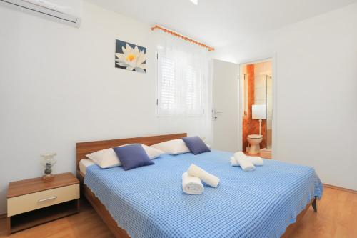 a white bedroom with a blue bed with two pillows at Apartments and rooms with parking space Kastel Stafilic, Kastela - 18673 in Kaštela