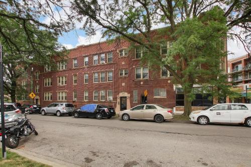 a group of cars parked in front of a brick building at Stylish Studio Apartment in Portage Park - Pensacola 2N in Chicago