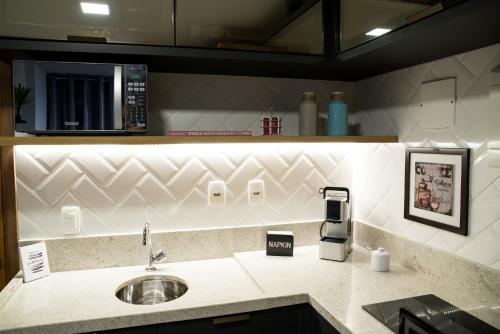 a kitchen counter with a sink and a microwave at SMART Flats - Decorado Superior - 11º andar - Esplanada - Saint Moritz in Brasilia