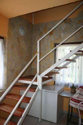 a white staircase in a room with a stone wall at Éva vendégház in Egerszalók