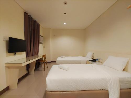 a hotel room with two beds and a desk at Kaizen Suites in Manila