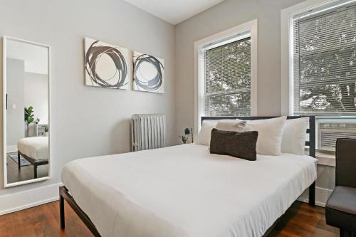 a bedroom with a large white bed and two windows at Modern Minimalist Studio Apt in Portage Park - Pensacola 3W in Chicago