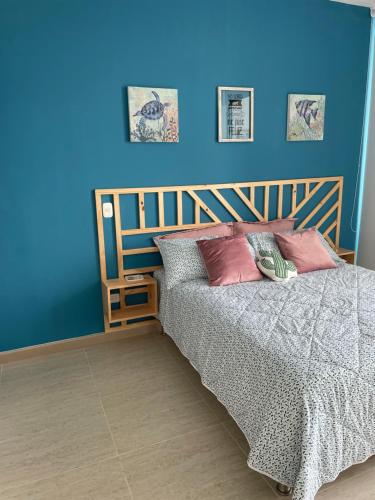Un dormitorio con una pared azul y una cama con almohadas en Espectacular Apartamento Sierra Beach Resort en Santa Marta