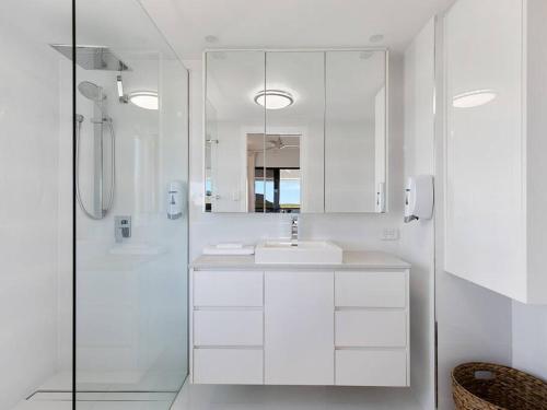 a white bathroom with a sink and a shower at 3 BEDROOM CBD WATERFRONT LUXURY APARTMENT in Cairns