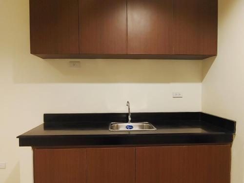 a kitchen counter with a sink and wooden cabinets at Kaizen Suites in Manila