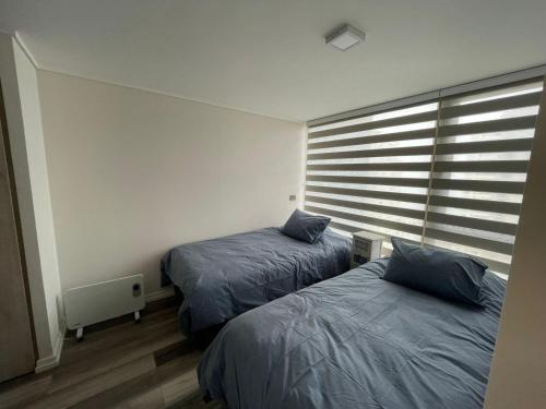 um quarto com 2 camas e uma janela com persianas em Departamento cercano a dunas y playa Concón em Concón