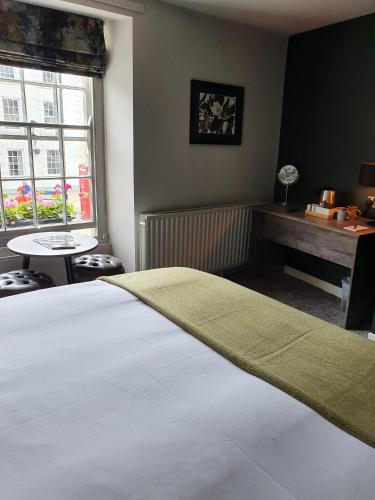 a bedroom with a bed and a table and a window at The Coach and Horses in Hexham