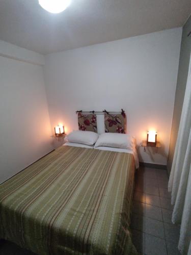 a bedroom with a bed with two pillows and two lights at Shaddai alojamientos in Salta