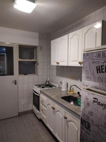 cocina con armarios blancos y nevera en Shaddai alojamientos en Salta