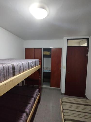 Habitación con 2 camas, armario y puerta. en Shaddai alojamientos en Salta