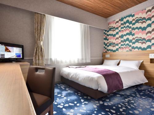 a bedroom with a bed and a desk and a television at Hotel WBF Kushiro in Kushiro