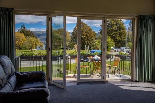 a living room with sliding glass doors with a table at Kea by the Lake in Te Anau