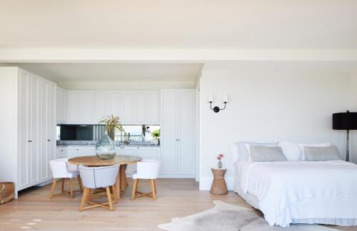 a bedroom with a bed and a table and a kitchen at THE CAPE at Wategos - Lodging in Paradise in Byron Bay