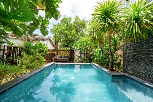 a swimming pool in a backyard with palm trees at Olala An Bang Villa in An Bang