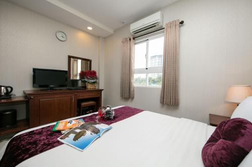 a bedroom with a bed and a tv and a bed sidx sidx sidx at Quy Hung Hotel Central in Ho Chi Minh City