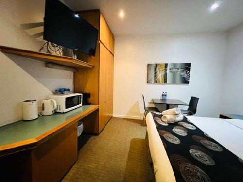 a hotel room with a bed and a microwave at 408 Lovely one BR ex hotel ensuite room in city in Adelaide