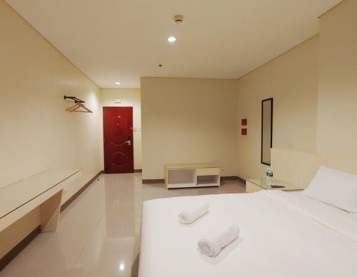 a bedroom with a white bed and a red door at Kaizen Suites in Manila