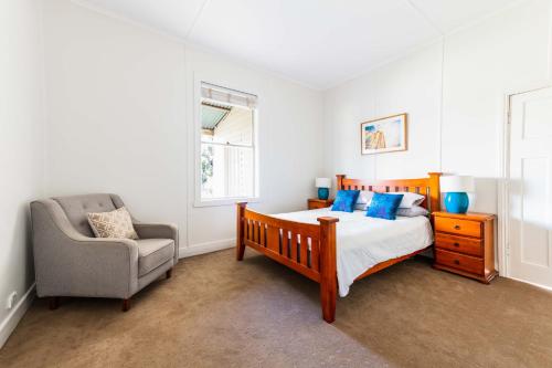un dormitorio con una cama y una silla en Pinkerton House, en Koorawatha