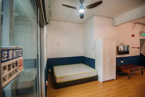 a small room with a bed and a ceiling fan at Bluewaters Pods 38 Hongkong St in Singapore
