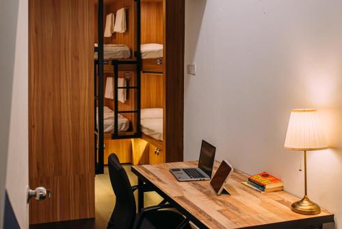a room with a desk with a laptop and a lamp at Bluewaters Pods 38 Hongkong St in Singapore
