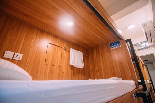a bedroom with a bed and a wooden wall at Bluewaters Pods 38 Hongkong St in Singapore