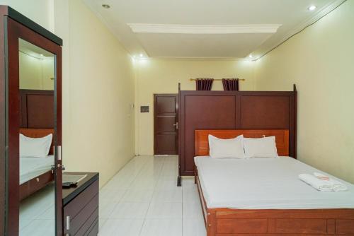 a bedroom with a large bed and a mirror at RedDoorz Syariah @ Jalan Bukit Kaminting 2 in Palangkaraya