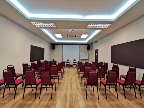 a conference room with red chairs and a screen at My Hotel Bukit Mertajam in Bukit Mertajam