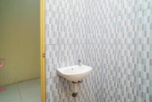 a bathroom with a sink in a tiled wall at RedDoorz Syariah @ Jalan Bukit Kaminting 2 in Palangkaraya