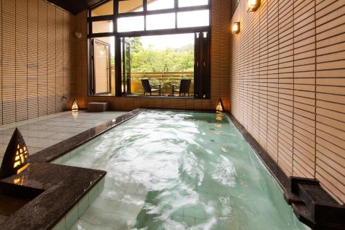 a hot tub in a room with a window at Kanazawa Hyakurakusou in Kanazawa
