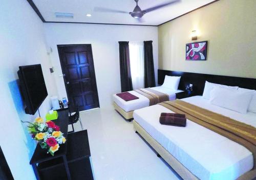 a hotel room with two beds and a television at Anjung Villa in Pantai Cenang