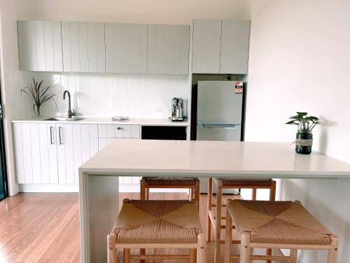 a kitchen with a large white island with chairs at Seven Peaks Farm Stay in Beerwah
