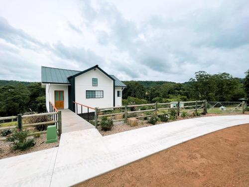 a white house with a fence next to a road at Seven Peaks Farm Stay in Beerwah
