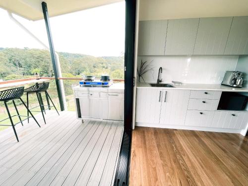 a kitchen with white cabinets and a balcony with a table at Seven Peaks Farm Stay in Beerwah