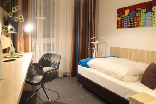 a hotel room with a bed and a chair at Gästehaus Wilhelmshöhe in Butzbach