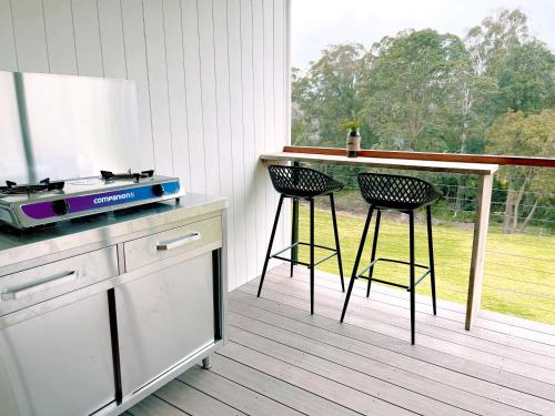 a kitchen with a counter and two stools at Seven Peaks Farm Stay in Beerwah