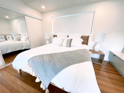 a bedroom with a large white bed with a large mirror at Seven Peaks Farm Stay in Beerwah