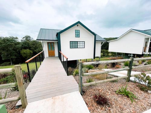 a small white house with a wooden walkway at Seven Peaks Farm Stay in Beerwah