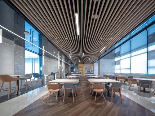 a cafeteria with tables and chairs and windows at Holiday Inn Express Shanghai Qingpu New City by IHG in Shanghai