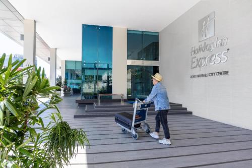 a man pushing a luggage cart in front of a building at Holiday Inn Express Kota Kinabalu City Centre, an IHG Hotel in Kota Kinabalu