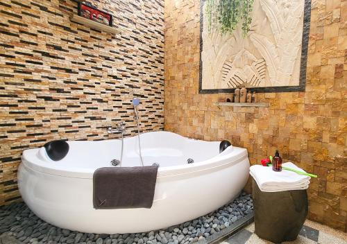 a bath tub in a bathroom with a brick wall at Verse Lite Hotel Gajah Mada in Jakarta