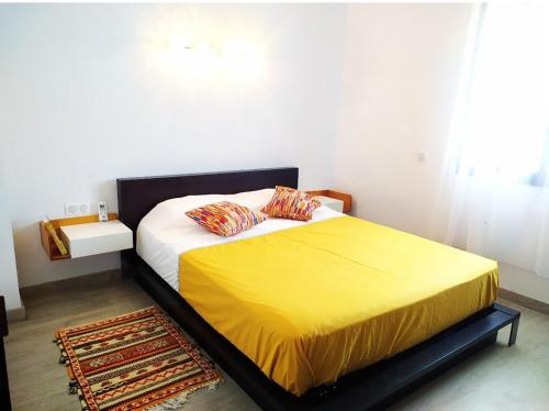 um quarto com uma cama com um cobertor amarelo em Taghazout bay - Tawenza Medina - Apt avec piscine partagée et Jardin em Tamraght Ouzdar