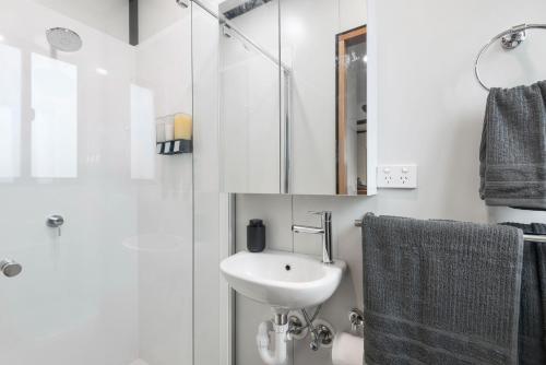 a white bathroom with a sink and a shower at Contained in Nimbin Accommodation in Nimbin