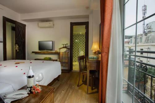 ein Hotelzimmer mit einem Bett, einem Schreibtisch und einem Fenster in der Unterkunft Free Airport Service Deals w Singita Classy Boutique Retreat & Travel in Hanoi