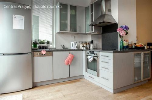 a kitchen with white cabinets and a refrigerator at Kent Ridge Loft in Prague