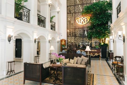 a lobby of a building with a couch and tables at MAHALAYA The Legacy Hotel in Solo