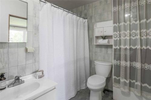 a white bathroom with a toilet and a sink at Gorgeous Lakefront 5-Bedroom Cottage 40min to TOR. in Manvers